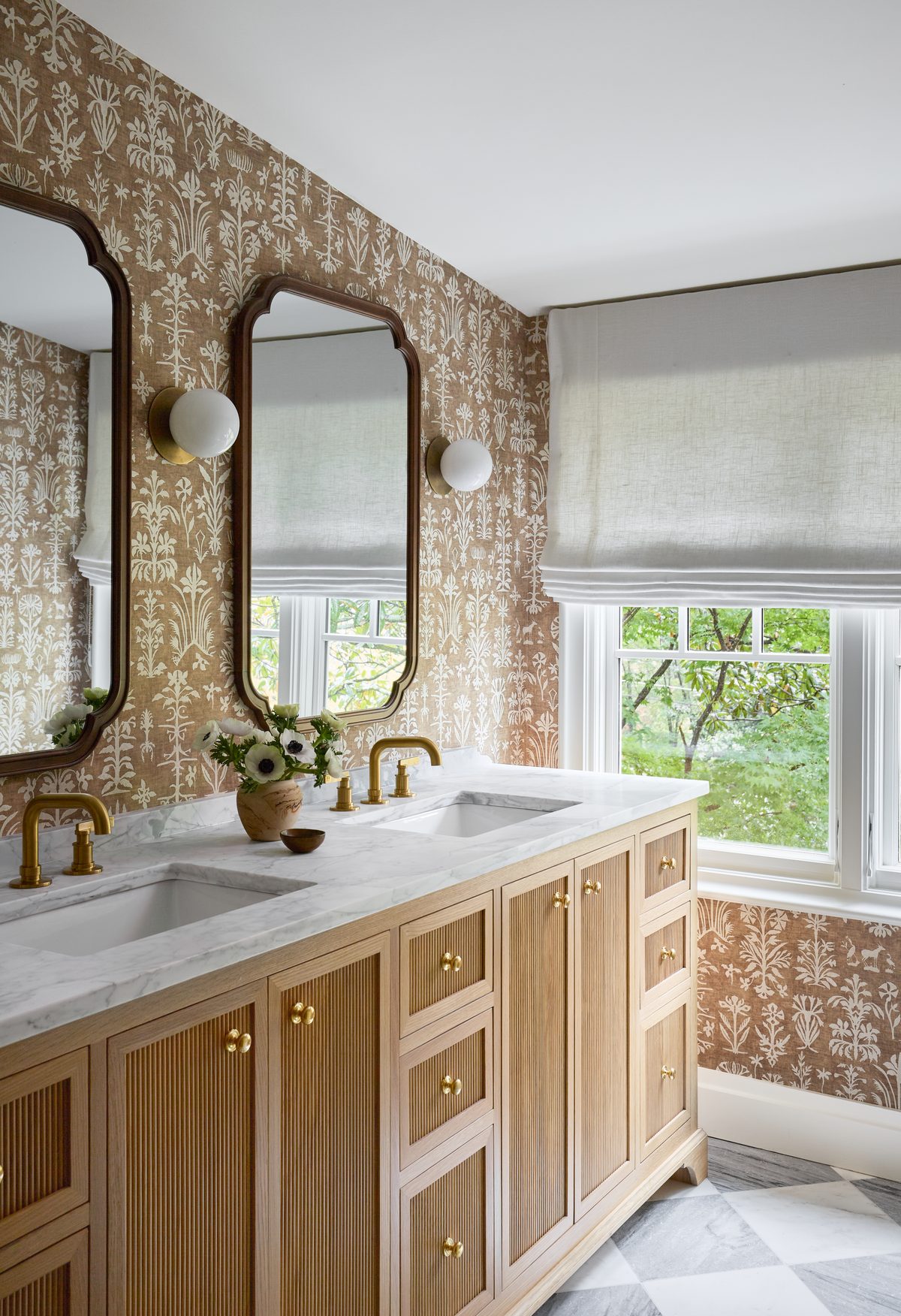 Primary bathroom with double vanity, brass fixtures, and floral wallpaper