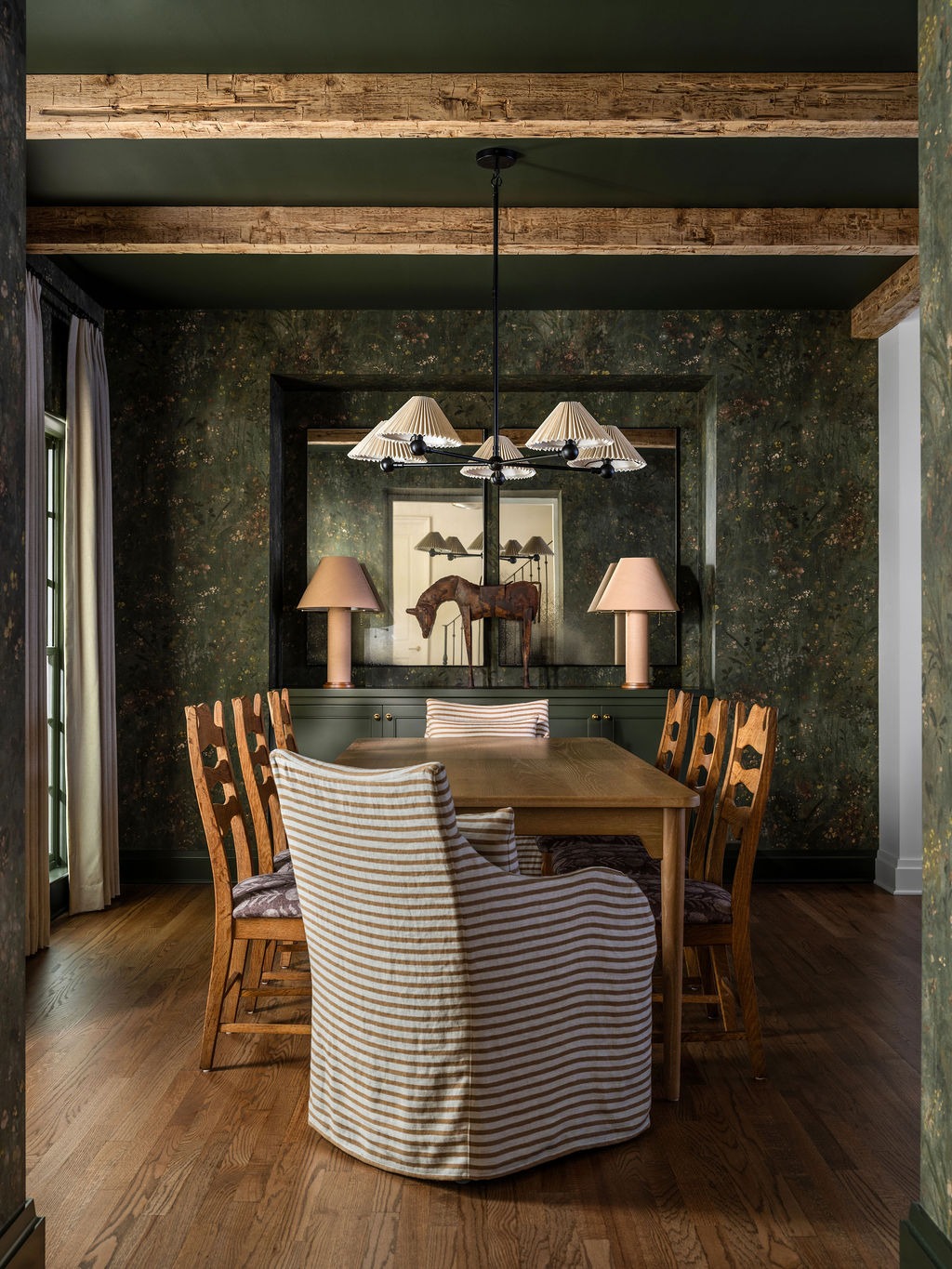 Dining room with dark botanical wallpaper, exposed beams, and brass chandelier